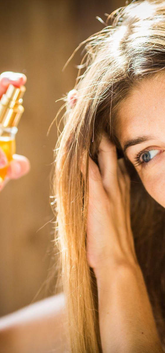Immagine di una ragazza bionda, che si sta applicando uno spray sui capelli
